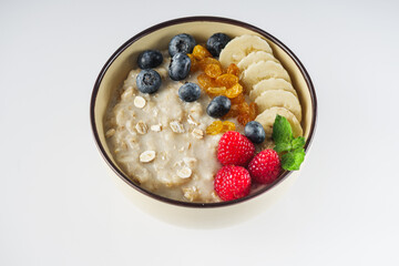 tasty nutritious oatmeal with fruits and berries on a white background