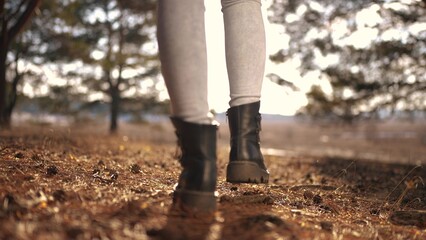 tourist girl walks through the forest. tourist recreation concept. female legs in black boots walk...