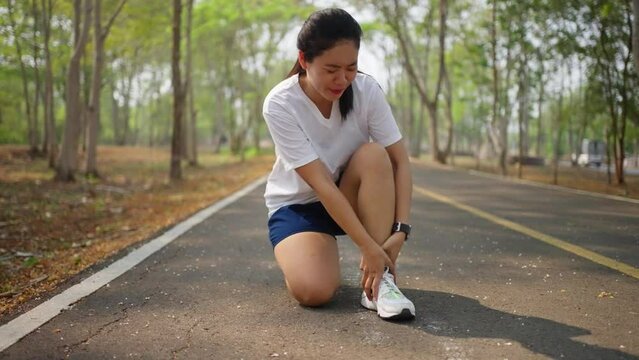 A female runner having painful leg cramp during her morning run at a public park