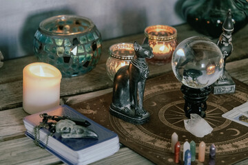 An atmospheric setting featuring a crystal ball, Egyptian cat statues, candles, and crystals,...