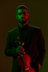 Elegant man playing violin in front of vibrant green and red background in a suit