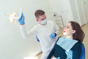 dentist examines the patient's mouth at a clinic appointment