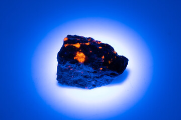 natural yooperlite gem stone in uv light on the white background