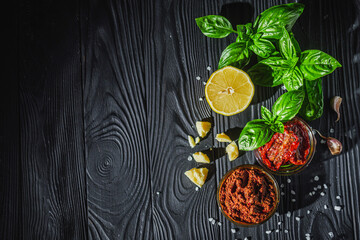 fresh pesto sauce with sun-dried tomatoes on a black wooden rustic background