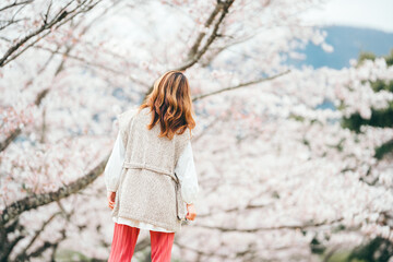 桜を見上げる茶髪の若い女性