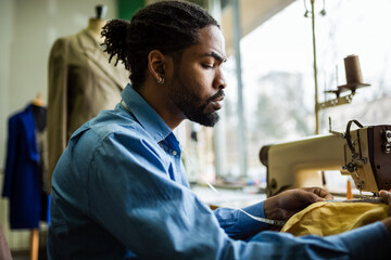 African American men fashion designer,tailor measuring fabric in his atelier.