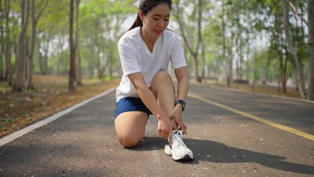 A female runner having painful leg cramp during her morning run at a public park