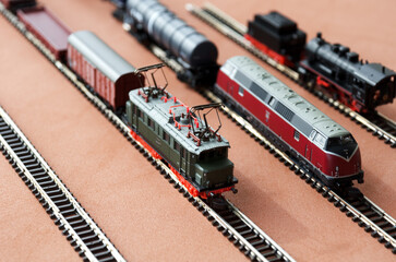 Toy passenger train and railroad with selective focus effect. Model of a locomotive on a dark background.
