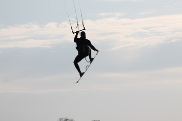 silhouette of a person jumping while kitesurfing