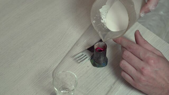 A jeweler pours plaster solution into a mold with a wax model.