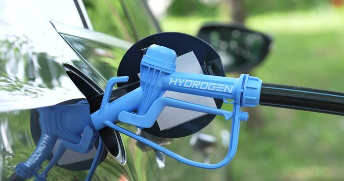 Close up of fuel cell car with connected hydrogen fueling nozzle