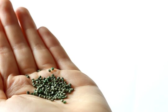 Hand mit Kunststoffgranulat vor wei&szlig;em Hintergrund symbolisiert den Rohstoff Plastik, Kunststoff und Polymere f&uuml;r die Kunststoffindustrie und die Kunststoffverarbeitung