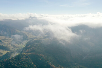 Aerial view of fluffy clouds over mountain forest