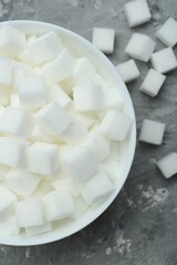 White sugar cubes in bowl on grey table, top view