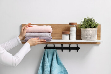 Woman stacking clean towels on shelf indoors, closeup