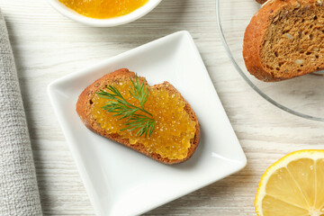 Slice of bread with pike caviar on white wooden table, flat lay
