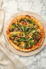 Delicious vegetarian pizza with mushrooms, vegetables and arugula on white marble table, top view