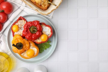 Delicious stuffed bell peppers served on white tiled table, top view. Space for text