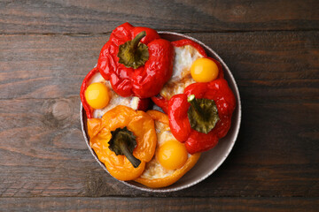 Delicious stuffed bell peppers with fried eggs on wooden table, top view