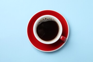 Aromatic coffee in cup on light blue background, top view