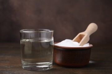 Vinegar in glass and baking soda on wooden table
