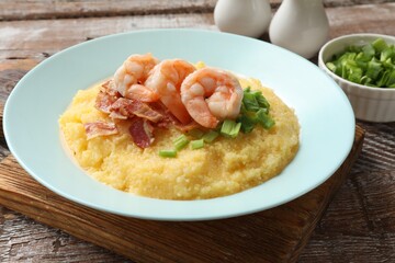 Plate with fresh tasty shrimps, bacon, grits and green onion on wooden table, closeup