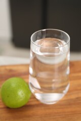 Filtered water in glass and lime on table in kitchen, closeup
