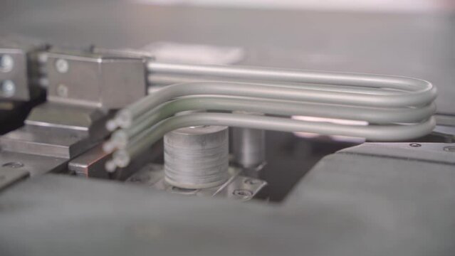 Factory production of heating element. Heating exchanger workshop. Industrial machine bending metal rod. Manufacturing heating element. Mass factory production.