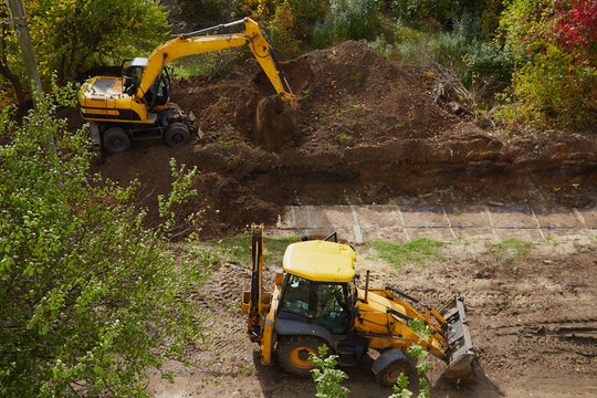 Bulldozer and excavator are carrying out construction work, construction site with excavator and bulldozer, construction and laying of the foundation of the house using construction equipment