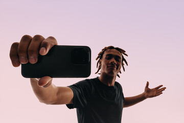 Portrait of a young man holding a smartphone and taking a selfie using a selfie camera app