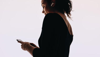 Woman streaming music on a mobile app, wearing wireless earbuds