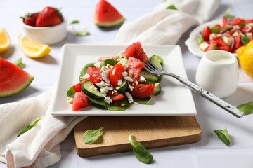 Watermelon salad in a bowl with lemon and strawberries on a white background
