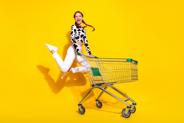Naklejka premium Full length photo of excited cheerful woman wear cow skin print top jumping enjoying shopping isolated yellow color background