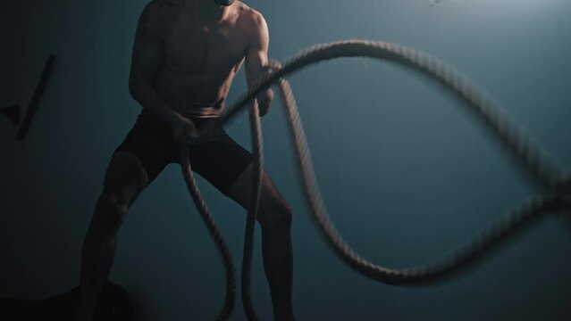 Guy whips ropes in wave motion at gym