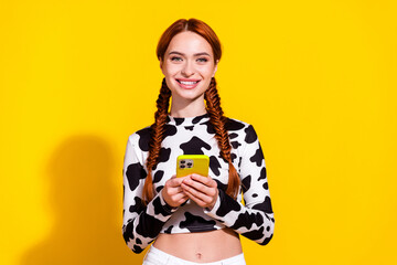 Photo of positive sweet woman wear cow skin print top texting sms modern gadget isolated yellow...