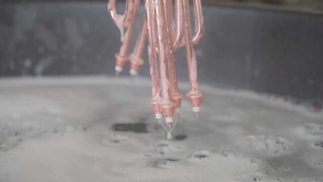 Factory production of heating element. Heating exchanger workshop. Washing and Polishing finished heating element, lowering the heater into the tub.