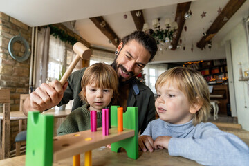 Cheerful loving father playing colorful blocks with his sons, spending free time together at home