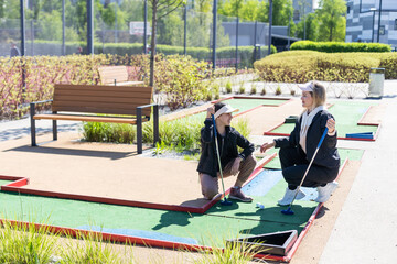 little girl and mother playing mini golf