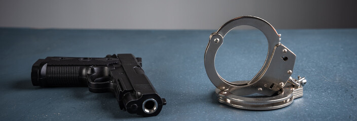 Gun and handcuffs on blue background, stock photo, criminal concept