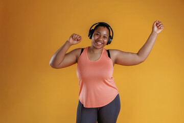 Front view, in headphones, listening to music. African American woman is in the studio against yellow background