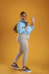 Bunch of fruits in the bag, holding. African American woman is in the studio against yellow background