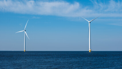 Two wind turbines stand tall in the middle of the ocean, harnessing the power of the wind to...