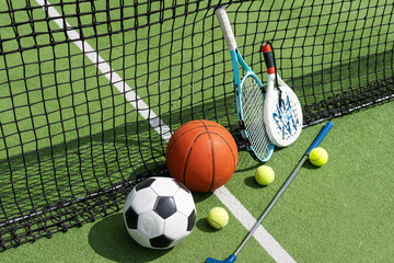 Obraz premium football soccer ball basketball tennis ball and racket laid on grass at sunset