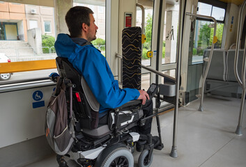 Man with disability with electric wheelchair on train. Inclusive and accessible public transportation concept.