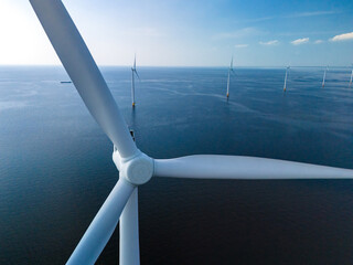 Windmills stand tall in the middle of the ocean, generating clean energy for the Netherlands from...
