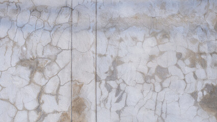 The old grunge concrete fence wall background with many crack lines texture and stains on surface