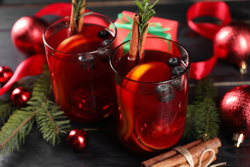 Aromatic Sangria drink in glasses, ingredients and Christmas decor on black wooden table