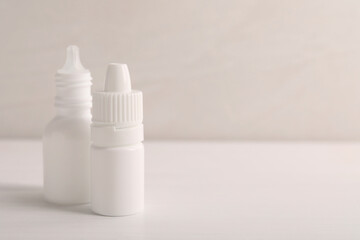 Bottles of medical drops on white background, space for text