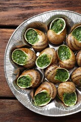 Delicious cooked snails on wooden table, top view