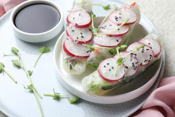 Delicious spring rolls, microgreens and soy sauce on table, closeup